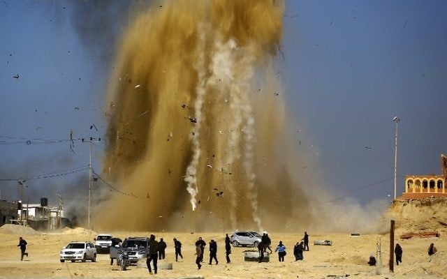 Les Palestiniens courent pour se protéger du nuage de sable et de la fumée suite à une attaque aérienne israélienne sur un poste du Hamas dans le nord de la bande de Gaza le 6 février 2017 (Crédit : Mohammed Abed / AFP)