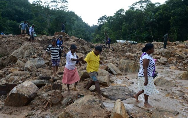 Les villageois sri lankais traversent un site touché par un glissement de terrain alors que les secouristes et les villageois cherchent des survivants dans le village d'Athweltota à Kalutara le 28 mai 2017. (Crédit : AFP PHOTO / LAKRUWAN WANNIARACHCHI) Les villageois sri lankais traversent un site touché par un glissement de terrain alors que les secouristes et les villageois cherchent des survivants dans le village d'Athweltota à Kalutara le 28 mai 2017. (Crédit : AFP PHOTO / LAKRUWAN WANNIARACHCHI)