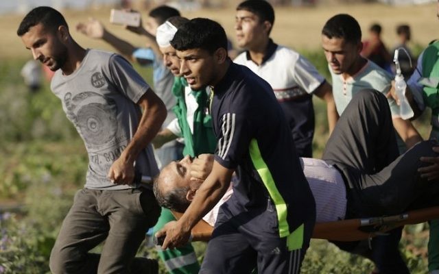 Des Palestiniens transportent un homme blessé pendant des affrontements contre l'armée israélienne près de la frontière entre la bande de Gaza et Israël, à l'est du camp de réfugiés de Jabalia, le 5 juin 2017. (Crédit : Mahmud Hams/AFP) Des Palestiniens transportent un homme blessé pendant des affrontements contre l'armée israélienne près de la frontière entre la bande de Gaza et Israël, à l'est du camp de réfugiés de Jabalia, le 5 juin 2017. (Crédit : Mahmud Hams/AFP)