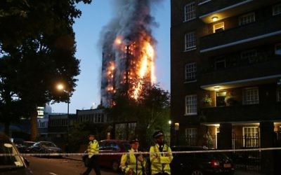 La police délimitant un périmètre de sécurité lors d'un violent incendie qui ravage la tour Grenfell, à Londres, le 14 juin 2017. (Crédit : Daniel Leal-Olivas/AFP Photo)