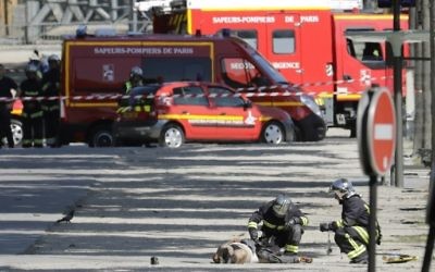 Secouristes penchés sur le corps d'un terroriste présumé dans une zone bouclée des Champs-Elysées, à Paris, le 19 juin 2017. (Crédit : Thomas Samson/AFP)
