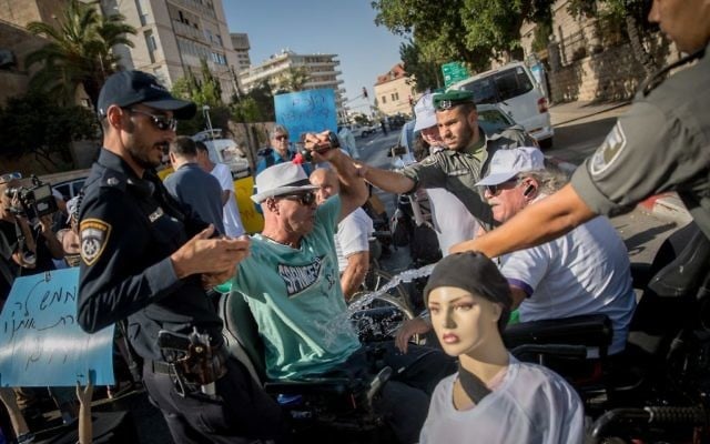 Un militant tentant de s'immoler pendant une manifestation contre la hausse insuffisante de l'allocation handicapé, devant la résidence du Premier ministre à Jérusalem, le 27 juin 2017. (Crédit : Yonatan Sindel/Flash90) Un militant tentant de s'immoler pendant une manifestation contre la hausse insuffisante de l'allocation handicapé, devant la résidence du Premier ministre à Jérusalem, le 27 juin 2017. (Crédit : Yonatan Sindel/Flash90)