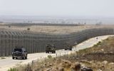 Des véhicules de l'armée israélienne le long de la route parallèle à la barrière de sécurité séparant les régions israélienne et syrienne du plateau du Golan, le 19 juillet 2017. (Crédit : Menahem Kahana/AFP)