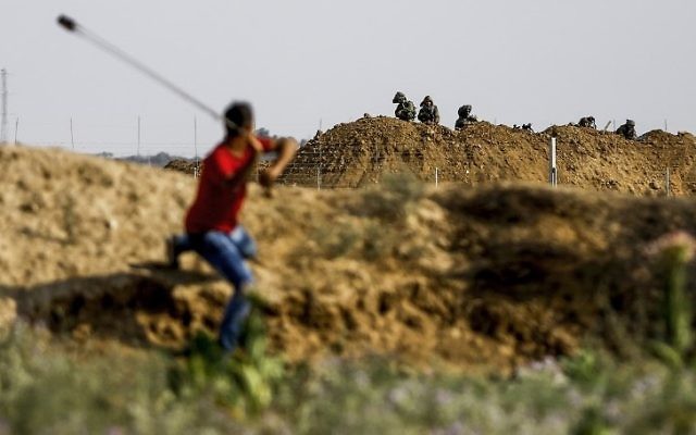 Un manifestant envoie une pierre aux troupes israéliennes durant des affrontements survenus à proximité de la barrière de sécurité de Gaza, à l'est du camp de réfugiés de Jabalia, le 21 juillet 2017, en protestation contre les nouvelles mesures de sécurité israéliennes sur le mont du Temple à Jérusalem (Crédit : AFP / MOHAMMED ABED) Un manifestant envoie une pierre aux troupes israéliennes durant des affrontements survenus à proximité de la barrière de sécurité de Gaza, à l'est du camp de réfugiés de Jabalia, le 21 juillet 2017, en protestation contre les nouvelles mesures de sécurité israéliennes sur le mont du Temple à Jérusalem (Crédit : AFP / MOHAMMED ABED)