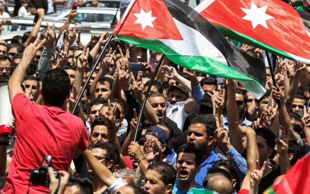 Des manifestants jordaniens brandissent des drapeaux nationaux et scandent des slogans durant une manifestation à proximité de l'ambassade israélienne dans la capitale d'Amman, le 28 juillet 2017, appelant à la fermeture de l'ambassade, au renvoi de l'ambassadeur et à l'annulation du traité de paix de 1994 avec Israël. (Crédit : KHALIL MAZRAAWI/AFP) Des manifestants jordaniens brandissent des drapeaux nationaux et scandent des slogans durant une manifestation à proximité de l'ambassade israélienne dans la capitale d'Amman, le 28 juillet 2017, appelant à la fermeture de l'ambassade, au renvoi de l'ambassadeur et à l'annulation du traité de paix de 1994 avec Israël. (Crédit : KHALIL MAZRAAWI/AFP)