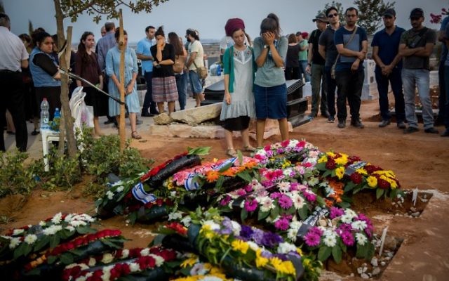 Des amis et des proches se recueillent sur la tombe de Yosef Salomon, 70 ans, sa fille Haya, 46 ans, et son fils Elad, 36 ans, après leurs funérailles qui ont réuni des milliers de personnes au cimetière de Modiin, le 23 juillet 2017 (Crédit : Yonatan Sindel/ FLASH90) Des amis et des proches se recueillent sur la tombe de Yosef Salomon, 70 ans, sa fille Haya, 46 ans, et son fils Elad, 36 ans, après leurs funérailles qui ont réuni des milliers de personnes au cimetière de Modiin, le 23 juillet 2017 (Crédit : Yonatan Sindel/ FLASH90)