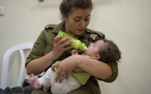 Une soldate israélienne donne le biberon à un bébé syrien en Israël, dans le cadre de l'opération Bon voisin d'aide humanitaire aux Syriens touchés par la guerre civile. Photographie non datée, publiée le 19 juillet 2017. (Crédit : unité des porte-paroles de Tsahal) Une soldate israélienne donne le biberon à un bébé syrien en Israël, dans le cadre de l'opération Bon voisin d'aide humanitaire aux Syriens touchés par la guerre civile. Photographie non datée, publiée le 19 juillet 2017. (Crédit : unité des porte-paroles de Tsahal)