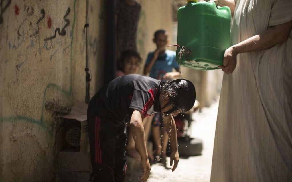 Un jeune palestinien se rafraichit avec de l'eau d'un bidon durant un pic de chaleur au camp de réfugiés al-Shati, à Gaza Ville, le 2 juillet 2017. (Crédit : AFP PHOTO / Mahmud Hams) Un jeune palestinien se rafraichit avec de l'eau d'un bidon durant un pic de chaleur au camp de réfugiés al-Shati, à Gaza Ville, le 2 juillet 2017. (Crédit : AFP PHOTO / Mahmud Hams)