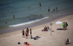 Des personnes profitant de la plage à Tel Aviv lors d'une chaude journée d'été, le 4 juillet 2017 (Crédit : Miriam Alster / Flash90)