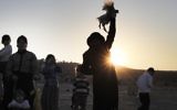 Un homme juif ultra orthodoxe tourne un poulet au-dessus des têtes des membres de sa famille lors de la cérémonie de Kaparot dans le quartier juif de Beit Shemesh à l'ouest de Jérusalem, le 28 septembre 2017 (Crédit : AFP PHOTO / MENAHEM KAHANA)