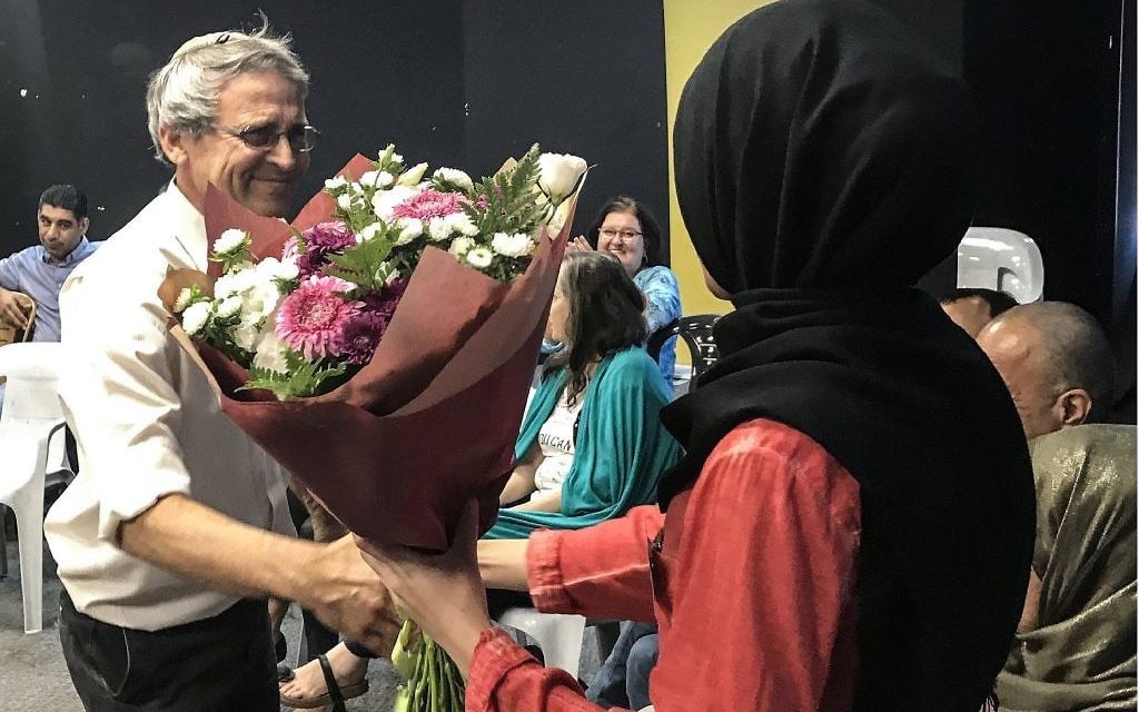 Le fondateur de Tag Meir, Gadi Gvaryahu, donne un bouquet de fleurs à Mervat Igbaria, étudiante qui a été confondue avec un terroriste lors d'un trajet d'autobus vers Beer Sheva (Crédit : Gabriel Carrol / Times of Israel)