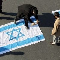Illustration : des manifestants iraniens versent du kérosène sur le drapeau israélien pendant l'enterrement du général de brigade Mohammad Ali Allahdi, à Tehéran, le 21 janvier 2015. (Crédit : AFP/Atta Kenare)