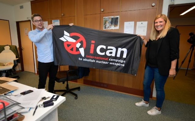 La directrice exécutive de l'ICAN, Beatrice Fihn (à droite) et le coordinateur Daniel Hogstan, tiennent une bannière avec le logo du groupe pour le désarmement nucléaire après que l'ICAN a remporté le prix Nobel de la paix pour sa campagne pour éliminer les armes nucléaires, le 6 octobre 2017, à Genève, Suisse (Crédit : AFP PHOTO / Fabrice COFFRINI)