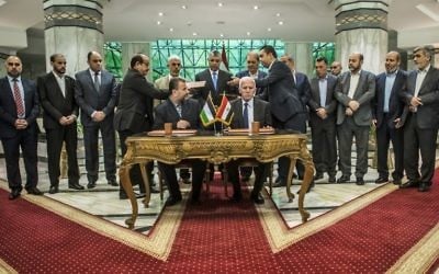 Saleh Arouri, assis à gauche, représentant du Hamas, et Azzam al-Ahmad, assis à droite, représentant du Fatah, pendant la signature d'un accord de réconciliation entre les factions palestiniennes rivales,  au Caire, le 12 octobre 2017. (Crédit : Khaled Desouki/AFP)