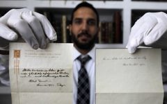 Gal Wiener, propriétaire gérant de la maison d'enchères Winner's de Jérusalem, présente deux notes écrites par Albert Einstein en 1922 sur le le papier de l'Imperial Hotel de Tokyo, le 19 octobre 2017. (Crédit : Menahem Kahana/AFP)