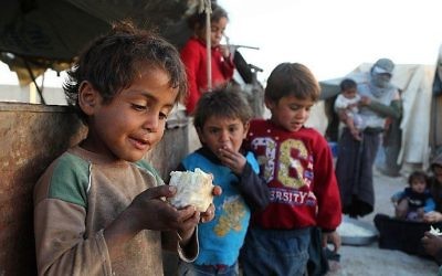 Un enfant syrien porte un morceau de chou-fleur à la bouche, dans le camp pour personnes déplacées de Ashari, dans la région orientale de la Ghouta, en périphérie de Damas, le 25 octobre 2017.  (Crédit : AFP / Amer ALMOHIBANY)