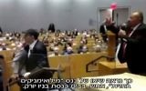 Bassem Eid, à droite, tente de parler pendant qu'un perturbateur est repoussé de la scène après avoir tenté de l'agresser dans une synagogue de New York, le 26 octobre 2017. (Crédit : capture d'écran Deuxième chaîne)