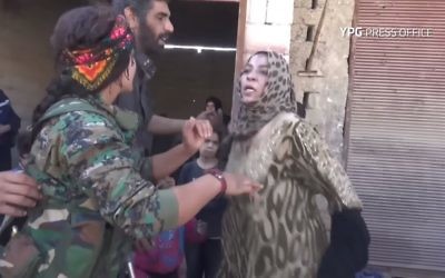 Une femme arrache les vêtements noirs imposés par l'Etat islamique pour célébrer la libération de Raqqa, le 13 octobre 2017. (Crédit : capture d'écran YouTube/YPG)