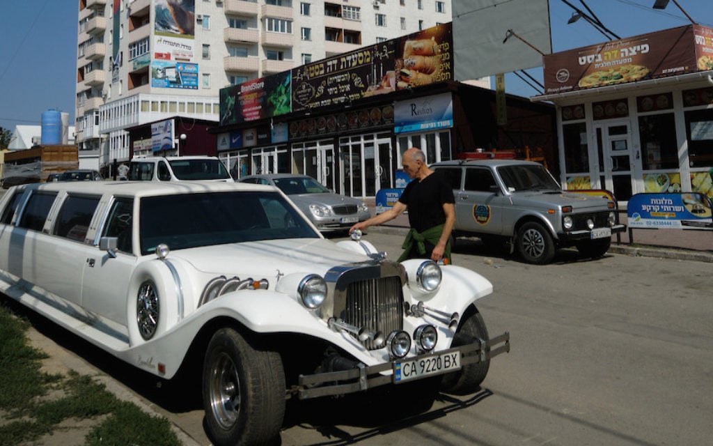 Un visiteur israélien à Ouman examine une limousine de luxe ukrainienne stationnée dans la rue Pushkin, largement habitée par des Juifs, le 8 septembre 2017 (Crédit :Cnaan Liphshiz/via JTA) Un visiteur israélien à Ouman examine une limousine de luxe ukrainienne stationnée dans la rue Pushkin, largement habitée par des Juifs, le 8 septembre 2017 (Crédit :Cnaan Liphshiz/via JTA)
