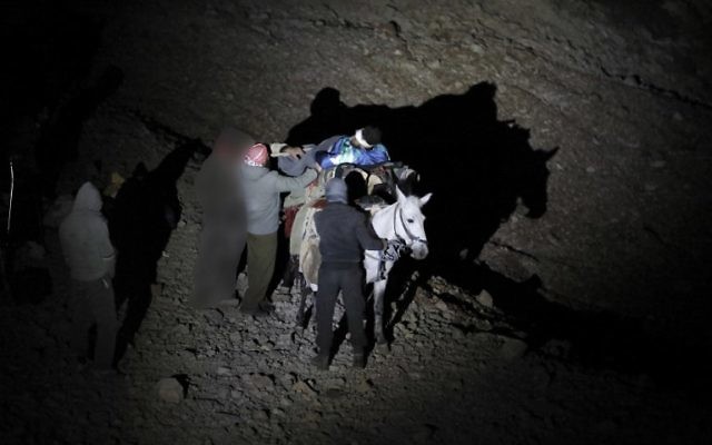 Un Syrien blessé transporté sur un âne à l'approche d'un point de rencontre avec des soldats israéliens sur le mont Hermon sur le plateau du Golan à la frontière entre Israël et la Syrie, avant d'être transféré vers un hôpital israélien pour traitement médical, le 26 octobre 2017 (Crédit : AFP / MENAHEM KAHANA)