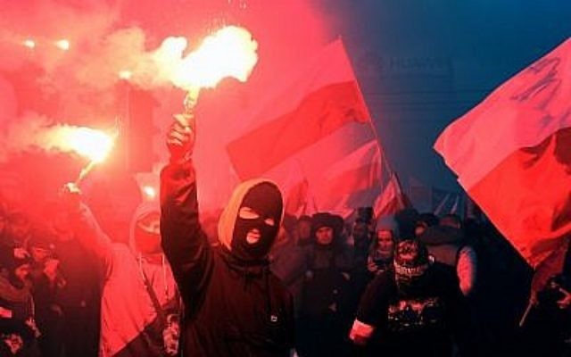 Des manifestants brûlent des torches et brandissent des drapeaux polonais durant une marche annuelle de commémoration de la Journée nationale de l'Indépendance à Varsovie, le 11 novembre 2017 (Crédit : AFP PHOTO / JANEK )