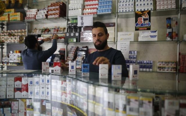 Des vendeurs palestiniens vendent des cigarettes dans un magasin de la ville de Gaza le 13 novembre 2017.
En vertu de l'accord conclu le mois dernier entre le Hamas et l'Autorité palestinienne, l'Autorité palestinienne a immédiatement mis au rancart les taxes et frais "illégaux" - ceux qui ont été imposés par le Hamas durant sa décennie de gouvernement. ainsi que des taxes sur d'autres biens tels que les cigarettes.
(Crédit : AFP / MOHAMMED ABED) Des vendeurs palestiniens vendent des cigarettes dans un magasin de la ville de Gaza le 13 novembre 2017.
En vertu de l'accord conclu le mois dernier entre le Hamas et l'Autorité palestinienne, l'Autorité palestinienne a immédiatement mis au rancart les taxes et frais "illégaux" - ceux qui ont été imposés par le Hamas durant sa décennie de gouvernement. ainsi que des taxes sur d'autres biens tels que les cigarettes.
(Crédit : AFP / MOHAMMED ABED)