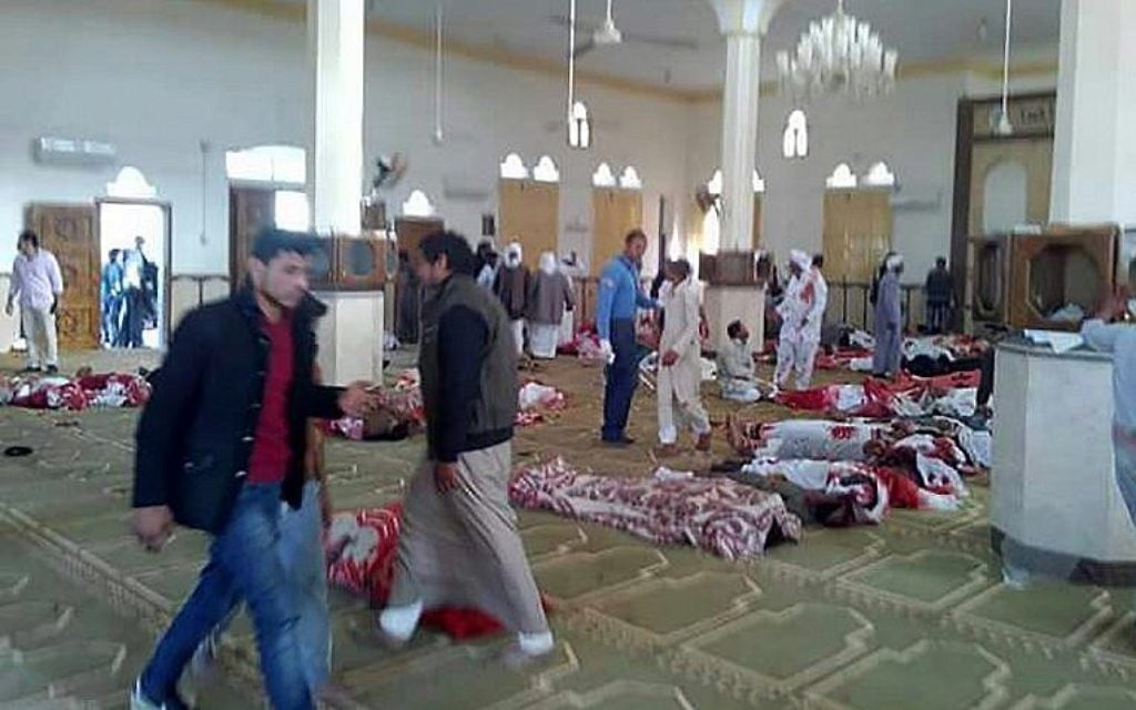 Des Egyptiens marchent autour des cadavres suite à un attentat à l'arme à feu et à la bombe commis dans la mosquée de  Rawda, à à peu-près 40 kilomètres à l'ouest de la capitale d'el-Arish, dans le nord du Sinaï, le 24 novembre 2017 (Crédit : AFP PHOTO / STRINGER)