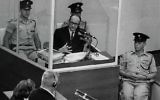 Le criminel de guerre nazi Adolph Eichmann dans une cabine de verre protectrice, entouré par la police israélienne, lors de son procès le 22 juin 1961 à Jérusalem. (Crédit : GPO)