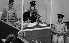 Le criminel de guerre nazi Adolph Eichmann dans une cabine de verre protectrice, entouré par la police israélienne, lors de son procès le 22 juin 1961 à Jérusalem. (Crédit : GPO)