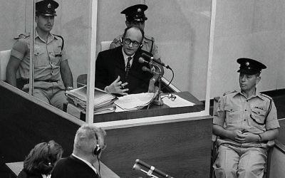 Le criminel de guerre nazi Adolph Eichmann dans une cabine de verre protectrice, entouré par la police israélienne, lors de son procès le 22 juin 1961 à Jérusalem. (Crédit : GPO)