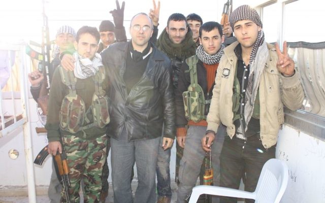 Jonathan Spyer, vêtu d'une veste en cuir noir, rencontre des combattants YPG kurdes dans le nord de la Syrie en 2013. (Crédit : autorisation)