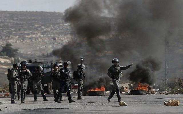 Les forces israéliennes prennent position au cours d'affrontements avec des manifestants palestiniens dans le village de Betunia, près de Ramallah, en Cisjordanie, le 7 décembre 2017 (Crédit : AFP PHOTO / ABBAS MOMANI) Les forces israéliennes prennent position au cours d'affrontements avec des manifestants palestiniens dans le village de Betunia, près de Ramallah, en Cisjordanie, le 7 décembre 2017 (Crédit : AFP PHOTO / ABBAS MOMANI)