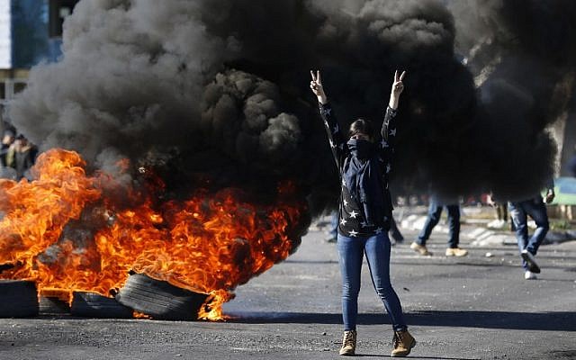 Un manifestant masqué palestinien lors d'affrontements avec les troupes israéliennes près d'un point de contrôle israélien dans la ville de Ramallah en Cisjordanie, le 8 décembre 2017 (Crédit : AFP PHOTO / ABBAS MOMANI)