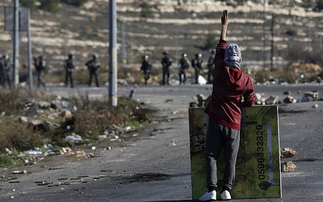 Un manifestant masqué palestinien lors d'affrontements avec les troupes israéliennes près d'un point de contrôle israélien dans la ville de Ramallah en Cisjordanie, le 8 décembre 2017 (Crédit : AFP PHOTO / ABBAS MOMANI)