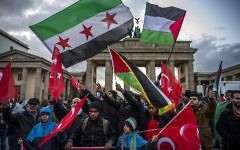 Des manifestants brandissent des drapeaux palestiniens, turques et syriens devant le Brandeburg Gate, près de l'ambassade américaine à Berlin, le 8 décembre 2017. (Crédit : John MACDOUGALL)