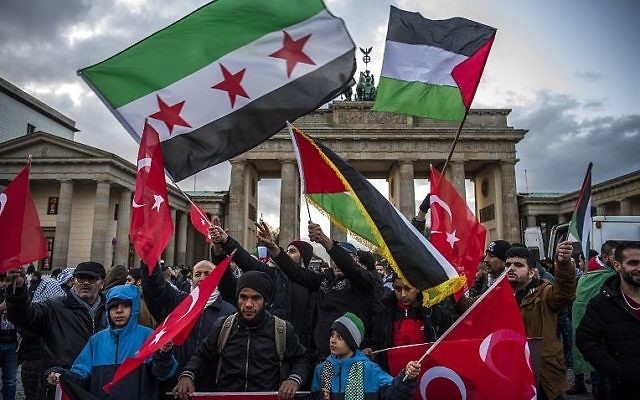 Des manifestants brandissent des drapeaux palestiniens, turques et syriens devant le Brandeburg Gate, près de l'ambassade américaine à Berlin, le 8 décembre 2017. (Crédit : John MACDOUGALL) Des manifestants brandissent des drapeaux palestiniens, turques et syriens devant le Brandeburg Gate, près de l'ambassade américaine à Berlin, le 8 décembre 2017. (Crédit : John MACDOUGALL)