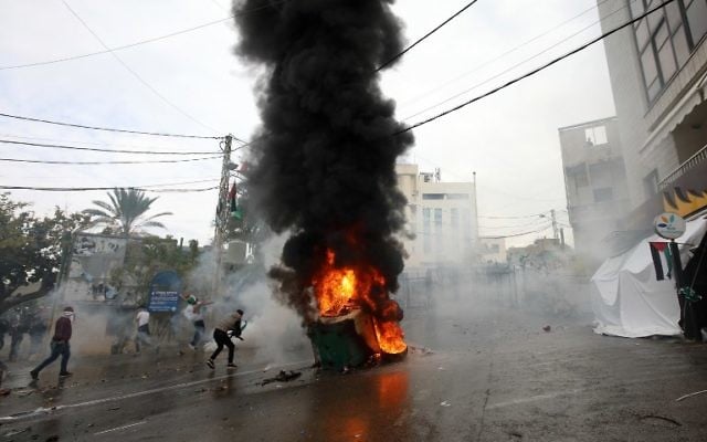 Les forces de sécurité libanaises lancent des gaz lacrymogènes pour disperser les manifestants alors qu'une benne à ordures est en feu lors d'une manifestation devant l'ambassade américaine à Awkar, aux abords de la capitale libanaise Beyrouth, le 10 décembre 2017. (AFP / ANWAR AMRO)