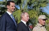 Le président syrien Bashar el-Assad, (à gauche), le président russe Vladimir Poutine et le ministre russe de la Défense Sergei Choigou inspectent un défilé militaire lors de leur visite à la base aérienne russe de Hmeimim, dans la province de Lattaquié, le 11 décembre 2017. (Crédit : Mikhail Klimentyev / AFP)