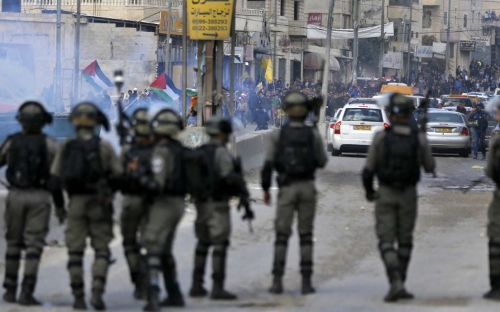 Les agents de police affrontent les émeutiers palestiniens durant des affrontements à proximité du poste de contrôle de Qalandiya en Cisjordanie, aux abords de Ramallah, le 15 décembre 2017 (Crédit : Abbas Momani/AFP) Les agents de police affrontent les émeutiers palestiniens durant des affrontements à proximité du poste de contrôle de Qalandiya en Cisjordanie, aux abords de Ramallah, le 15 décembre 2017 (Crédit : Abbas Momani/AFP)