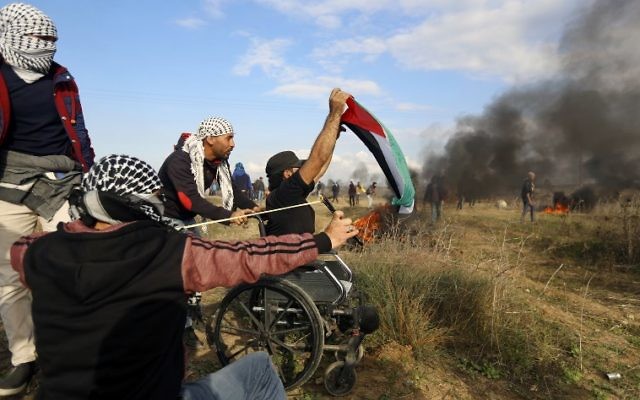 Le manifestant palestinien handicapé Ibrahim Abu Thurayeh brandit un drapeau palestinien durant une manifestation le long de la frontière avec Gaza le 15 décembre 2017 dans des affrontements qui suivent la reconnaissance de Jérusalem comme capitale d'Israël du président américain Donald Trump (Crédit : MOHAMMED ABED / AFP) Le manifestant palestinien handicapé Ibrahim Abu Thurayeh brandit un drapeau palestinien durant une manifestation le long de la frontière avec Gaza le 15 décembre 2017 dans des affrontements qui suivent la reconnaissance de Jérusalem comme capitale d'Israël du président américain Donald Trump (Crédit : MOHAMMED ABED / AFP)