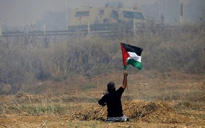 Le manifestant palestinien Ibrahim Abu Thurayeh brandit un drapeau palestinien lors d'affrontements avec des soldats israéliens près de la barrière frontalière à l'est de la ville de Gaza, le 19 mai 2017. (Crédit : AFP / MOHAMMED ABED / Archives)