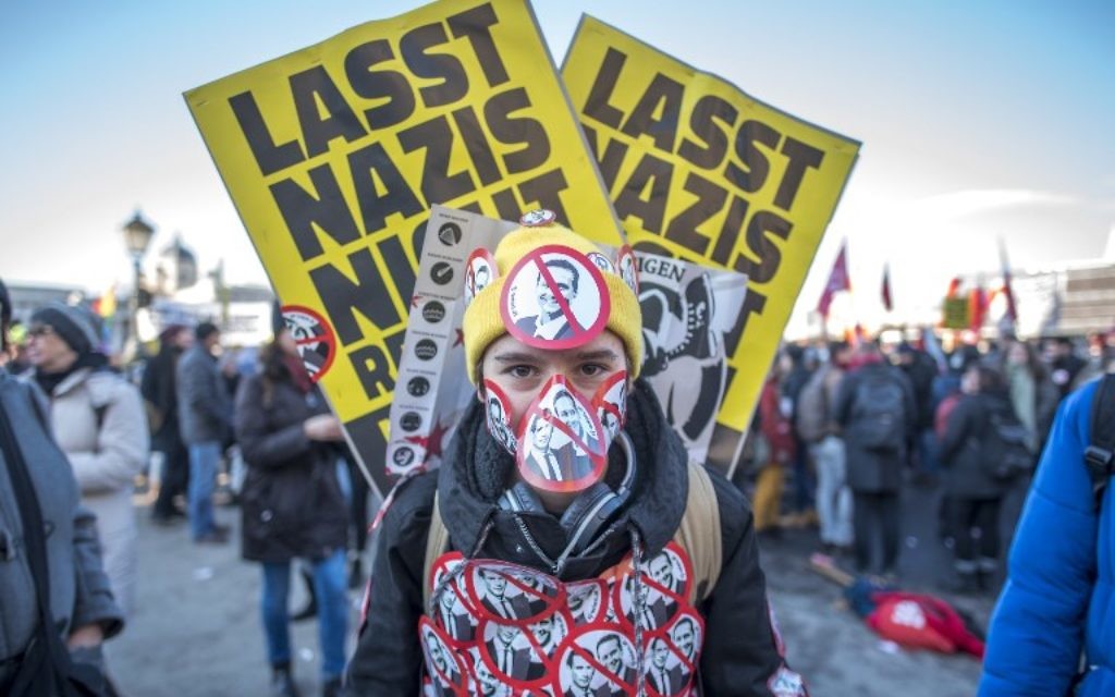 Un manifestant bardé d'autocollants dépeignant le prochain vice-chancelier du parti d'extrême-droite de la Liberté Christian Strache et le prochain chancelier issu du parti populaire (OeP) Sebastian Kurz durant une manifestation aux abords du palais présidentiel pendant la cérémonie d'investiture du nouveau gouvernement, le 18 décembre 2017 (Crédit : AFP PHOTO / JOE KLAMAR) Un manifestant bardé d'autocollants dépeignant le prochain vice-chancelier du parti d'extrême-droite de la Liberté Christian Strache et le prochain chancelier issu du parti populaire (OeP) Sebastian Kurz durant une manifestation aux abords du palais présidentiel pendant la cérémonie d'investiture du nouveau gouvernement, le 18 décembre 2017 (Crédit : AFP PHOTO / JOE KLAMAR)