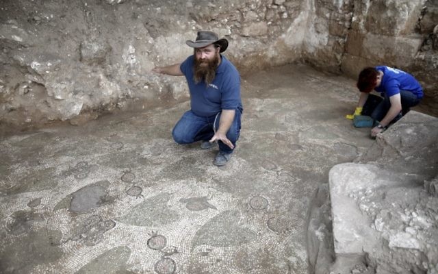 Benyamin Storchan, directeur des fouilles pour l'Autorité israélienne des antiquités, montre un sol décoré, vestige d'un monastère de l'ère byzantine, à Beit Shemesh, le 20 décembre 2017. (Crédit : AFP / MENAHEM KAHANA Benyamin Storchan, directeur des fouilles pour l'Autorité israélienne des antiquités, montre un sol décoré, vestige d'un monastère de l'ère byzantine, à Beit Shemesh, le 20 décembre 2017. (Crédit : AFP / MENAHEM KAHANA