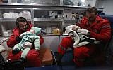 Des ambulanciers syriens distraient des enfants dans une ambulance, pendant la deuxième nuit de l’opération d’évacuation coordonnée par le Croissant rouge syrien et le CICR, à Douma, dans la région de la Ghouta orientale, le 27 décembre 2017. (Crédit : AFP/ABDULMONAM EASSA)