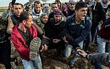 Des manifestants palestiniens transportent un blessé durant un affrontement contre les forces israéliennes près de la frontière entre Israël et Gaza dans la ville de Khan Yunis, dans le sud de Gaza, le 29 décembre 2017 (Crédit :  AFP PHOTO / SAID KHATIB)