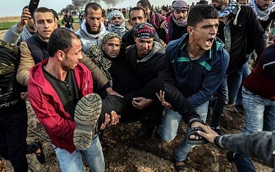 Des manifestants palestiniens transportent un blessé durant un affrontement contre les forces israéliennes près de la frontière entre Israël et Gaza dans la ville de Khan Yunis, dans le sud de Gaza, le 29 décembre 2017 (Crédit :  AFP PHOTO / SAID KHATIB)
