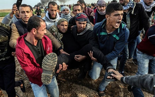 Des manifestants palestiniens transportent un blessé durant un affrontement contre les forces israéliennes près de la frontière entre Israël et Gaza dans la ville de Khan Yunis, dans le sud de Gaza, le 29 décembre 2017 (Crédit : AFP PHOTO / SAID KHATIB) Des manifestants palestiniens transportent un blessé durant un affrontement contre les forces israéliennes près de la frontière entre Israël et Gaza dans la ville de Khan Yunis, dans le sud de Gaza, le 29 décembre 2017 (Crédit : AFP PHOTO / SAID KHATIB)