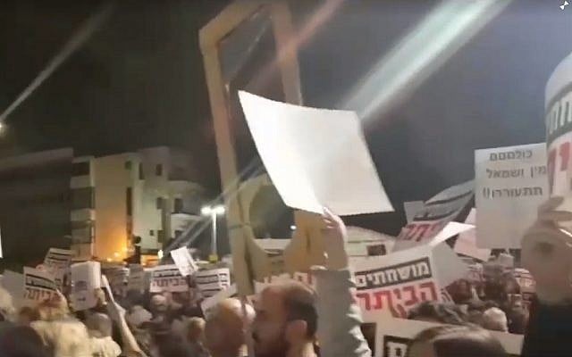 Un homme brandissant une fausse guillotine en carton assiste à un rassemblement anti-Netanyahu à Tel Aviv le 23 décembre 2017 (Crédit : capture d'écran 0404.co.il)