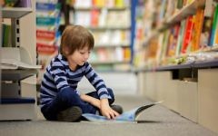 Photo d'illustration d'un petit garçon assis dans une librairie en train de lire (Crédit : tatyana_tomsickova/ IStock by Getty Images)