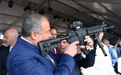 Le ministre de la Défense Avigdor Liberman inspecte le viseur d'un fusil dans une usine d'armement à Sderot, le 14 décembre 2017. (Crédit : Ariel Hermoni/Defense Ministry)